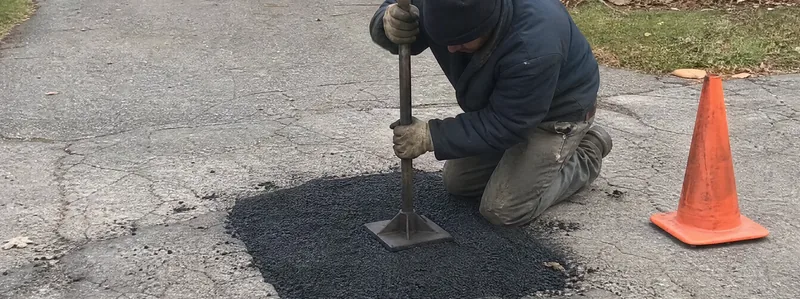 Worker patching a pothole in asphalt driveway Arvada Colorado
