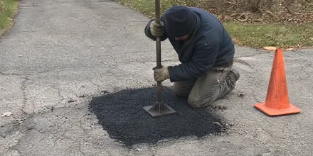 Crew repairing a pothole in an asphalt driveway in Arvada CO